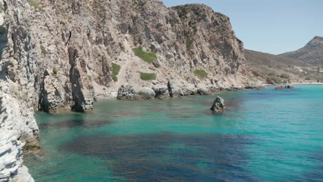 Slow-Dolly-Aerial-in-between-rock-formations-in-Turquoise-Blue-Ocean-Water-on-Greek-Island-Milos