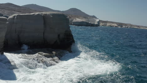 Fast-Drone-Flight-Through-Rock-Formation-at-Sarakiniko-Lunar-Volcanic-Beach-with-Waves-crashing-on-rocks-in-Milos,-Greece