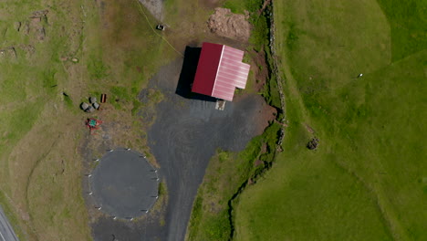 Top-down-birds-eye-view-of-a-rural-farmhouse-in-countryside-of-Iceland.-Overhead-aerial-view-of-an-isolated-house-in-grassland-of-Iceland