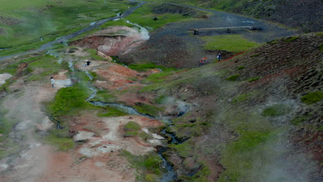 Vista-Aérea-De-Drones-área-Geotérmica-En-Islandia-Con-Paisaje-De-Cráteres-Humeantes-Y-Exploración-Turística.-Ojo-De-Pájaro-De-Fumarolas-Y-Cráteres-De-Agua-Caliente