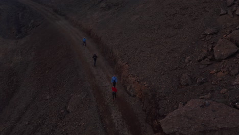 Aerial-view-four-people-backpacker-hiking-exploring-isolated-landscape-in-Iceland.-Drone-view-friends-tourist-walking-pathway-in-rocky-icelandic-desert