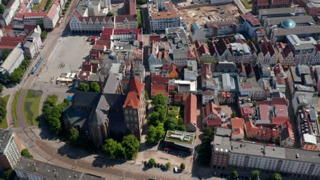 Aerial-view-of-Saint-Marys-church-in-historic-city-centre.-Orbit-shot-of-basilica.-Tram-stopping-at-stop-at-city-hall