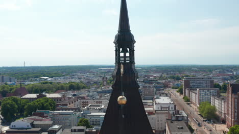 Close-up-shot-of-church-steeple-lantern.-Fly-around-top-of-tower-with-bell.-Panoramic-aerial-view-of-city