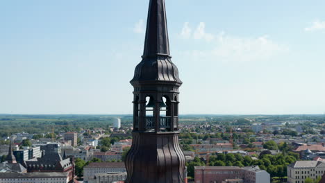 Orbit-shot-around-church-steeple-steel-lantern-with-bell.-Panning-aerial-view-of-city
