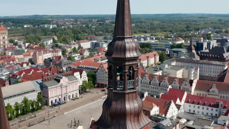 Pan-and-tilt-down-footage-of-church-tower-and-historic-city-centre-with-square,-gabled-houses-and-city-hall-in-backgrounds