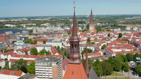 Panoramic-aerial-view-of-town-and-surrounding-water-surface.-Orbit-shot-around-top-of-church-tower