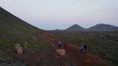 Aerial-view-orbit-of-group-of-sporty-people-walking-pathway-in-isolated-extreme-panorama-in-Iceland.-Drone-view-four-people-hikers-mountaineering-in-icelandic-isolated-rocky-desolate-panorama