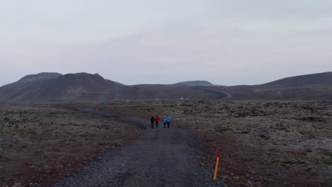 Birds-eye-drone-view-four-people-walking-isolated-trail-in-Iceland-highlands.-Aerial-view-group-of-hikers-trekking-in-wild-icelandic-nordic-countryside