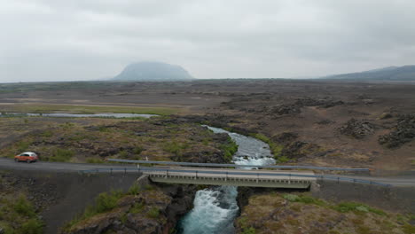 Drohnenansicht-Fluss,-Der-über-Felsige-Und-Trostlose-Landschaft-In-Island-Fließt.-Luftbild-Isländische-Landschaft-Mit-Felsformationen-Und-Fluss,-Der-Unter-Der-Ringstraßenbrücke-Fließt