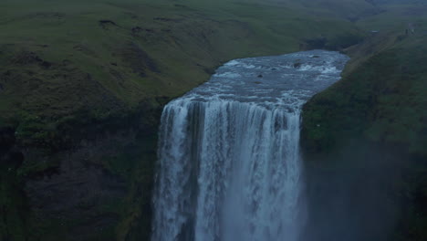 Aerial-drone-view-of-Skogafoss-waterfall,-one-of-the-most-famous-in-south-Iceland.-Birds-eye-over-Skoga-river-jumping-into-cascade-in-icelandic-foggy-misty-day.-Skogafoss-waterfall