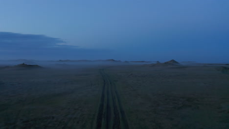 Aerial-view-car-parked-in-grassy-misty-countryside-in-Iceland.-Dramatic-foggy-misty-drone-of-moonscape-valley-in-Iceland