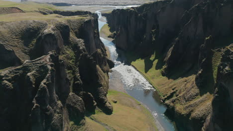 Aerial-breathtaking-view-of-canyon-with-river-gently-flowing-in-Iceland.-Amazing-drone-view-flying-through-icelandic-canyon-covered-with-green-moss.-Beauty-in-nature