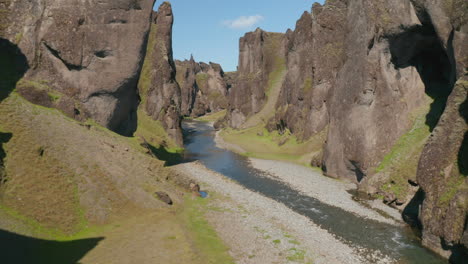 Amazing-drone-flying-through-icelandic-canyon-covered-with-green-moss.-Amazing-on-earth.-Birds-eye-of-rugged-countryside-cliffs-in-Iceland-with-river-flowing-through-it
