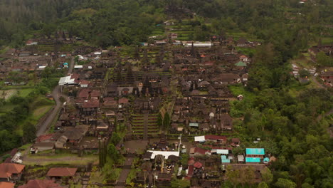 Aerial-view-of-ancient-religious-buildings-at-Besakih-Temple-in-Bali,-Indonesia.-Circling-shot-of-tourists-exploring-the-famous-Hindu-temple-with-tall-pagodas
