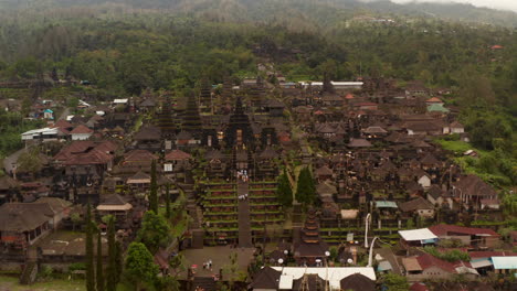 Aerial-dolly-view-of-tourists-exploring-the-Besakih-Temple-in-Bali,-Indonesia.-People-at-the-famous-tourist-destination-viewing-the-religious-buildings-and-structures-in-famous-Hindu-temple