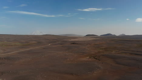 Birds-eye-view-of-dramatic-desert-landscape-in-Iceland.-Aerial-drone-view-of-rocky-and-dusty-panorama-of-icelandic-highlands-with-gravel-trail-path-and-mountains-in-background