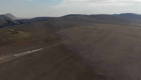 Aerial-view-car-driving-in-desert-stony-highlands-in-Iceland.-Drone-view-vehicle-4x4-speeding-off-road-on-pathway-in-rocky-volcanic-icelandic-desert.-Commercial-insurance