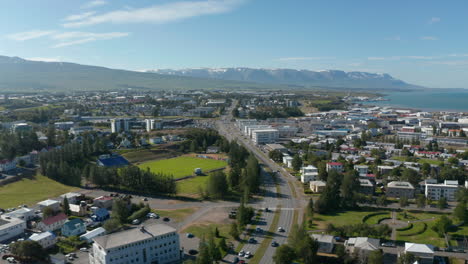 Aerial-panoramic-footage-of-town.-Trunk-road-leading-around-football-playground.-Buildings-in-urban-borough.-Akureyri,-Iceland