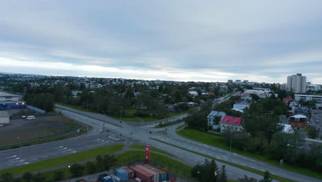 Fly-above-intersection-and-multilane-road-in-residential-borough.-Lots-of-greenery-in-town.-Reykjavik,-Iceland