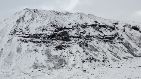 AERIAL:-Snow-White-Mountain-with-Black-Rocks-in-Iceland-Winter,-Snowing,-Cold,-Arctic