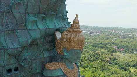 Garuda-Wisnu-Kencana-statue-in-Bali,-Indonesia.-Close-up-aerial-view-of-the-face-of-Hindu-deity-Vishnu-riding-Garuda.-Giant-copper-blue-and-green-religious-statue