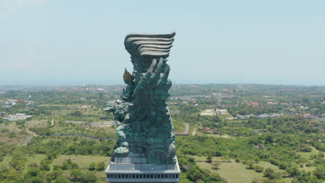 Side-view-of-huge-copper-statue-in-Bali,-Indonesia.-Garuda-Wisnu-Kencana-statue-rising-above-the-city