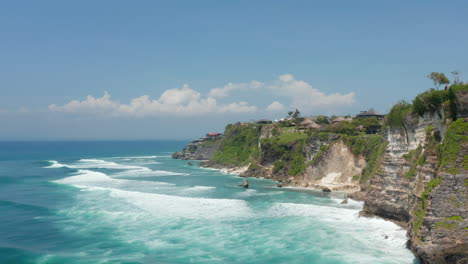 Luxury-villas-and-vacation-homes-on-top-of-steep-ocean-cliffs-in-Bali,-Indonesia.-Aerial-view-of-tropical-resort-on-stunning-rocky-coastline