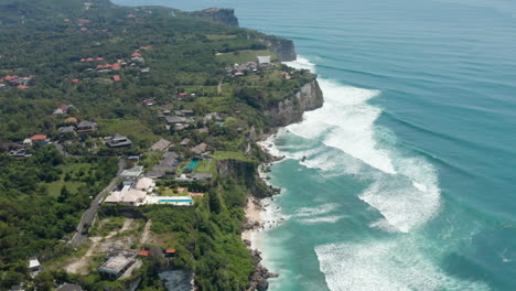 Luxury-tropical-villas-and-holiday-homes-with-pools-on-top-of-the-cliff-above-turquoise-blue-sea-in-Bali,-Indonesia
