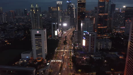 Aerial-shot-of-traffic-on-the-multi-lane-highway-through-the-modern-city-center-in-the-night-in-Jakarta,-Indonesia