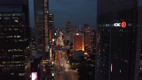 Aerial-dolly-shot-descending-towards-night-time-traffic-on-Selamat-Datang-Monument-roundabout-in-Jakarta,-Indonesia