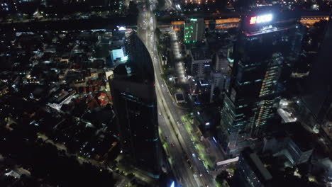 Aerial-tilting-shot-following-busy-traffic-on-multi-lane-road-through-downtown-Jakarta-at-night