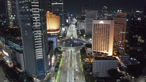 Aerial-pedestal-tilting-view-of-Selamat-Datang-Monument-roundabout-with-fast-car-traffic-through-downtown-Jakarta-at-night