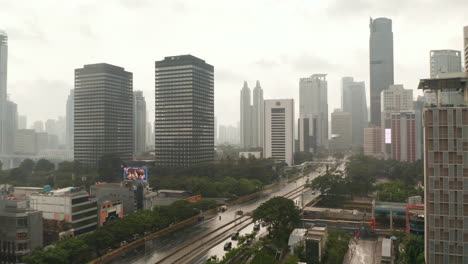 Aerial-dolly-shot-flying-across-a-multi-lane-road-into-the-city-on-a-wet-rainy-day-in-Jakarta,-Indonesia