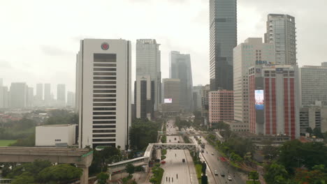 Aerial-dolly-shot-following-traffic-on-a-multi-lane-highway-into-the-city-with-tall-skyscrapers-on-a-wet-rainy-day-in-Jakarta,-Indonesia