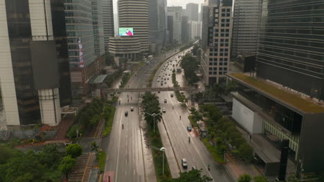 Aerial-low-flying-dolly-into-pedestal-shot-of-multi-lane-traffic-driving-into-the-city-center-on-a-wet-rainy-day-in-Jakarta,-Indonesia