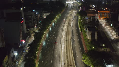 Absteigende-Sockelluftaufnahme-Von-Knappen-Autos,-Die-Nachts-Während-Der-Covid-19-Pandemie-In-Jakarta-Auf-Einer-Leeren-Autobahn-Fahren