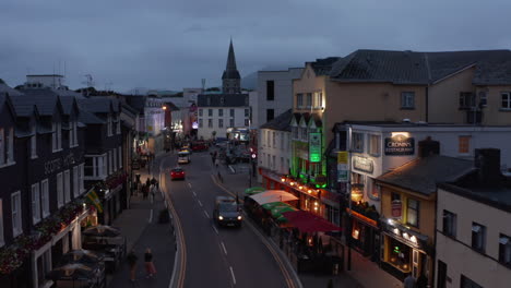 People-walking-in-evening-town.-Outdoor-terraces-in-front-of-restaurants-on-street.-City-at-dusk.-Killarney,-Ireland-in-2021