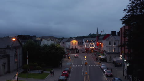 Aerial-ascending-shot-of-town-at-twilight,-overcast-sky.-Vehicles-passing-through-street.-Killarney,-Ireland-in-2021