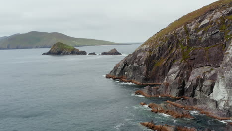 Forwards-fly-along-rugged-rocky-coast.-Rippled-sea-and-mild-waves-washing-shore.-Amazing-natural-scenery.-Ireland