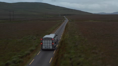 Forwards-tracking-of-offroad-car-with-horse-trailer-driving-on-narrow-road-in-countryside.-Pastures-and-grasslands-along-road.-Ireland