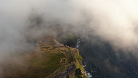 Aerial-footage-of-coastal-cliffs-shrouded-in-low-clouds.-Picturesque-golden-hour-scenery.-Cliffs-of-Moher,-Ireland