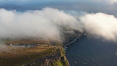 Aerial-panoramic-shot-of-high-cliffs-shrouded-in-low-clouds.-Romantic-natural-scenery-of-sea-coast-at-golden-hour.-Cliffs-of-Moher,-Ireland