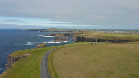 Fly-above-meadow-above-high-cliffs-steeply-falling-to-sea-surface.-Aerial-panoramic-footage-of-natural-landmark.-Kilkee-Cliff-Walk,-Ireland