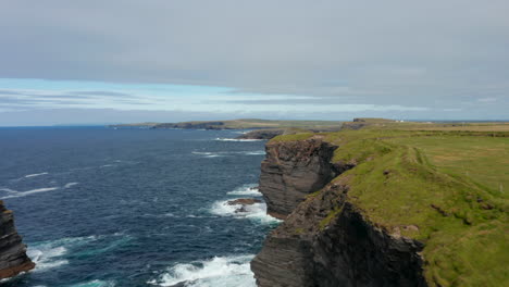 Forwards-fly-above-high-and-steep-cliffs.-Waves-crashing-on-coast.-Breath-taking-nature-scenery.-Kilkee-Cliff-Walk,-Ireland
