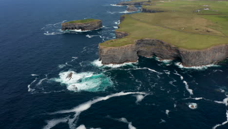 Aerial-panoramic-footage-of-sea-coast-with-waves-crashing-on-rocky-cliffs-and-outcrops.-Kilkee-Cliff-Walk,-Ireland
