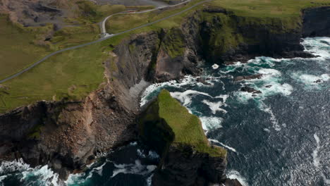 High-angle-view-of-boiling-water-at-sea-coast.-Waves-rolling-and-crashing-on-shore.-Green-meadows-above-high-steep-slopes.-Kilkee-Cliff-Walk,-Ireland