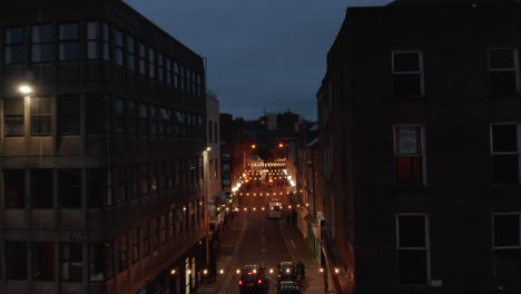 Forwards-fly-above-illuminated-narrow-street-in-city-centre.-Decorative-light-chains-across-aisle.-Night-scene.-Limerick,-Ireland