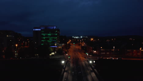 Forwards-fly-above-road-leading-on-bridge.-Revealing-illuminated-sport-stadium.-Night-city-scene.-Limerick,-Ireland