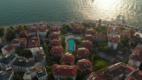 Hotel-Resort-on-Bosphorus-Riverside-with-view-on-Maiden's-Tower-in-beautiful-Afternoon-light,-Slow-forward-Aerial-tilt-down