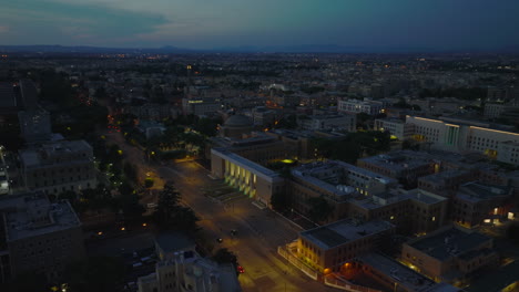 Aerial-slide-and-pan-footage-of-University-Sapienza-complex-at-night.-Illuminated-streets-and-tall-entrance-gate-to-grounds.-Rome,-Italy